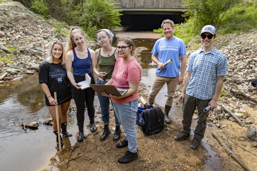 UNC students, under the direction of Mike Piehler, gather data from a creek next to Eastgate Shopping Center on April 14, 2022, in Chapel Hill as a part of the Sustainable Triangle Field Site project through the Institute for the Environment. Piehler, the director of the Institute for the Environment, along with second-year postdoc Adam Gold helped advise the students as they took water level measurements and gathered data for the program’s capstone project.(Johnny Andrews/UNC-Chapel Hill)