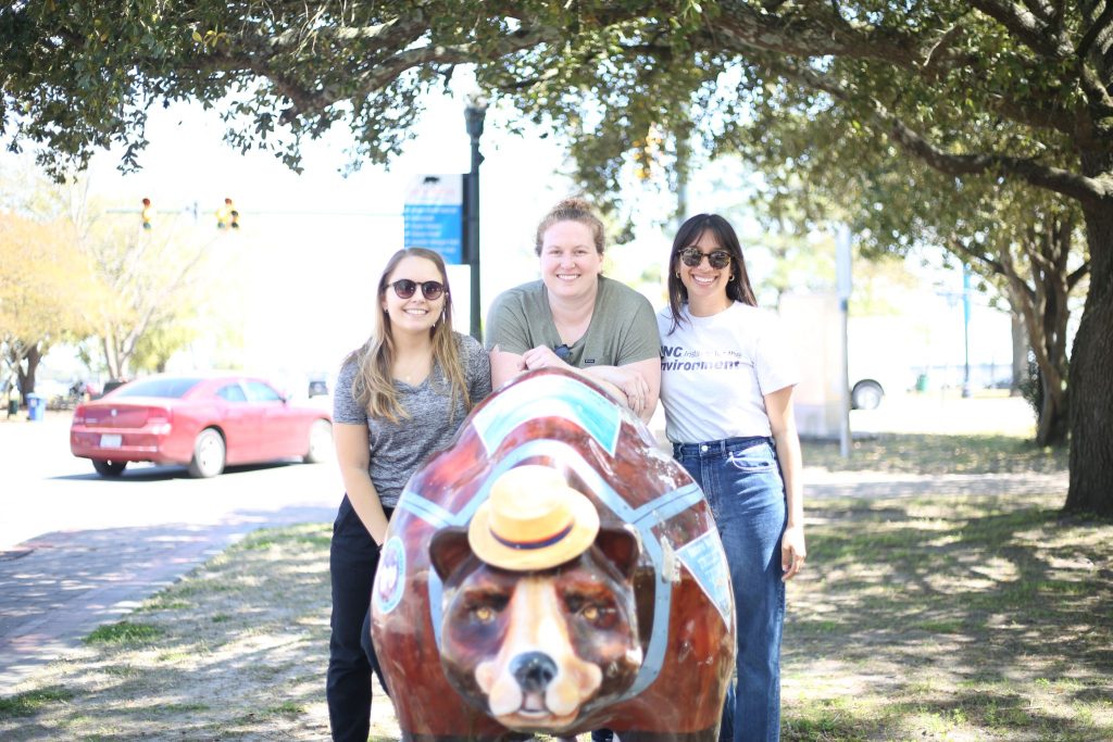 women smiling with bear statue