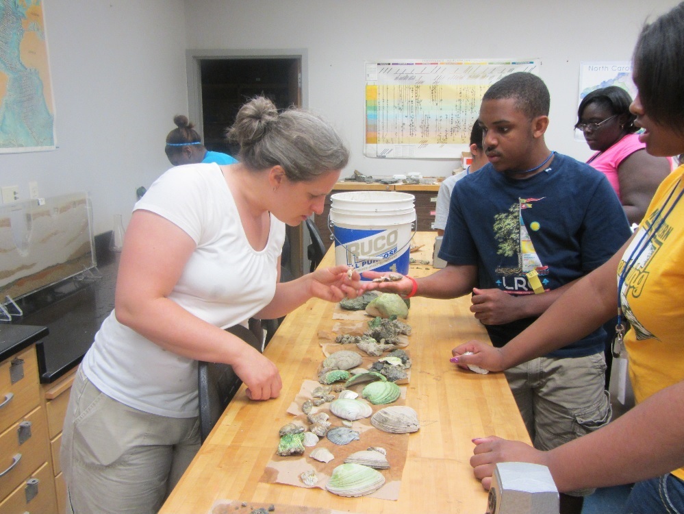Megan Hughes with students in a lab looking at fossils