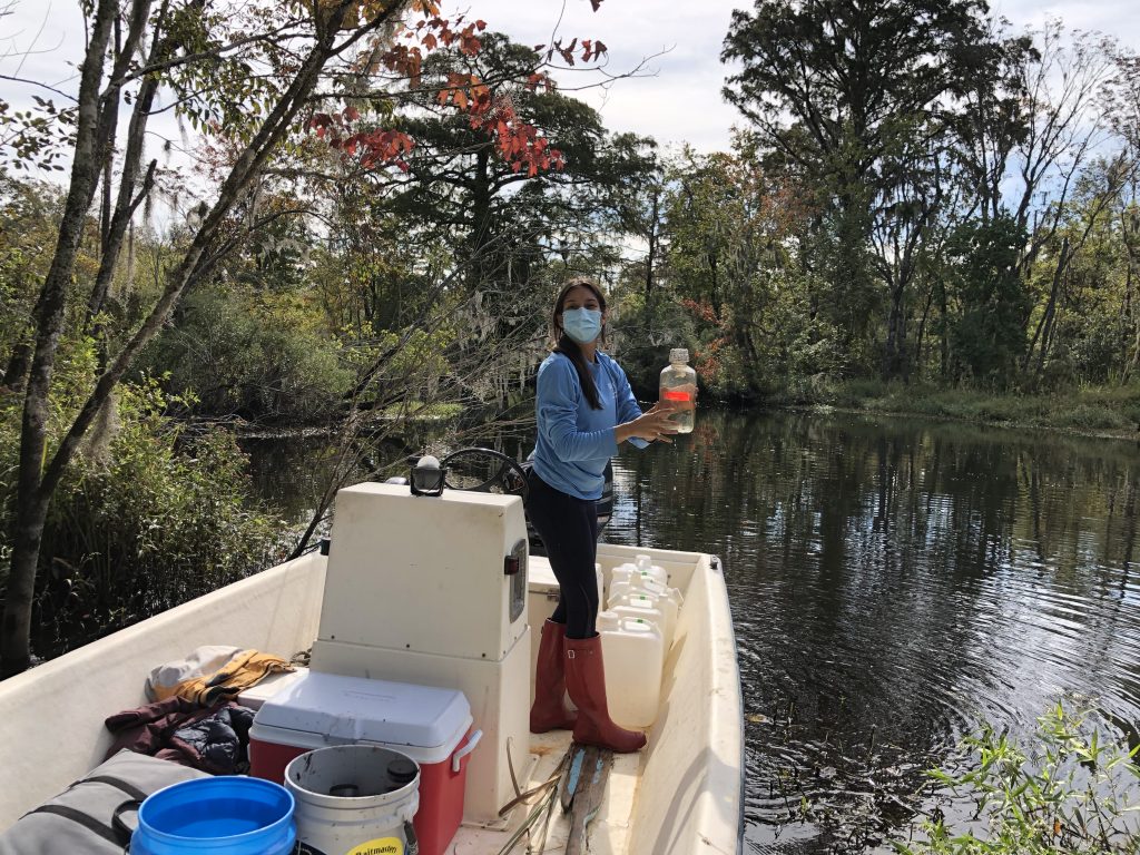 Anne Smiley in a boat taking samples in a pond.